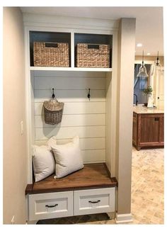 a bench with two baskets on it and some white drawers in the back ground area