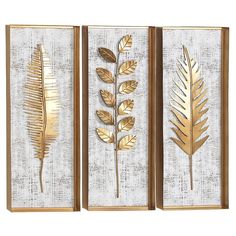 three gold metal wall art pieces with leaves on white and brown wood paneled panels