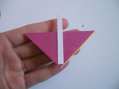 a hand holding a piece of pink paper with a white strip sticking out of it