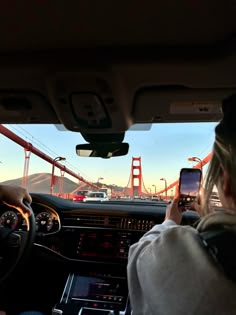 a person is driving in front of the golden gate bridge and taking a photo with their cell phone