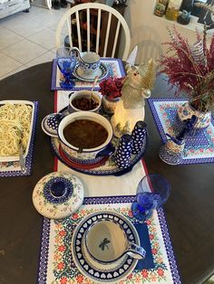 the table is set with plates, bowls and dishes on it's placemats