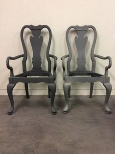 two grey chairs sitting next to each other on top of a cement floored floor