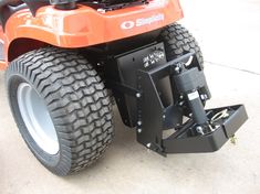 an orange lawn mower sitting on top of a sidewalk