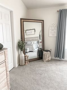 a mirror sitting on top of a wooden dresser next to a bed in a bedroom