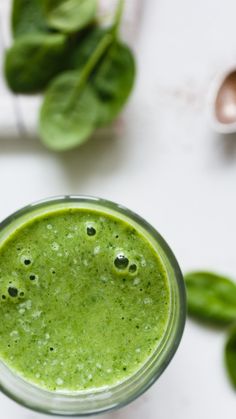 a green smoothie with spinach leaves on the side