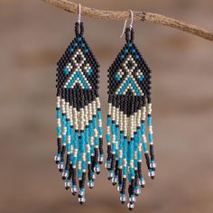 two pairs of beaded earrings hanging from a tree branch