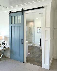 an open door leading to a bathroom with wood flooring and white walls in the background