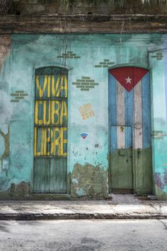 an old building painted in blue and green with two doors on each side that have the words viva luba libre written on them