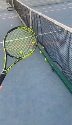 a person holding a tennis racquet on top of a tennis court with balls