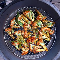 some food is cooking on a grill with broccoli florets and other vegetables