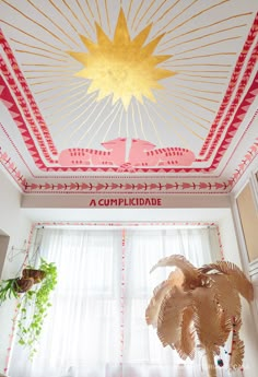 the ceiling in this room is decorated with red and gold decorations, including a large fan