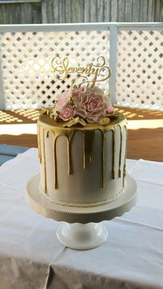 a white and gold cake sitting on top of a table next to a wooden fence