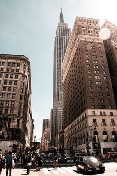 people crossing the street in front of tall buildings