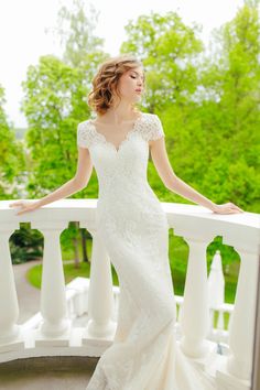 a woman in a wedding dress standing on a balcony