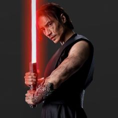 a man holding a red light saber in his right hand and looking at the camera