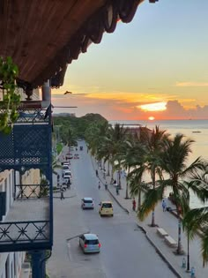 the sun is setting over the ocean and palm trees