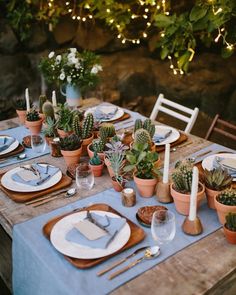 the table is set with succulents, plates and utensils for dinner