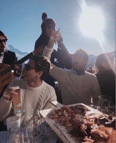 a group of people sitting around a table with food and drinks