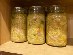 three jars filled with food sitting on top of a wooden shelf