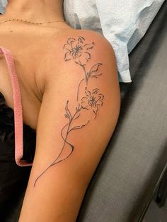 a woman with a flower tattoo on her arm sitting in a chair next to a pillow