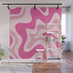 a pink and white abstract wall mural in an office space with wooden flooring, shelving unit and potted plant