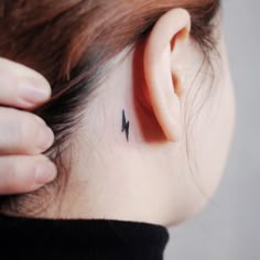 a woman's left ear has a small black arrow tattoo on it