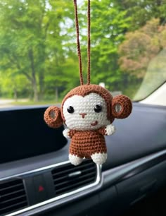 a crocheted monkey hanging from the dashboard of a car