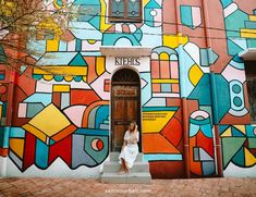 a woman standing in front of a colorful building