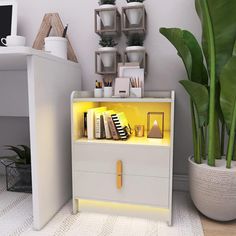 a white desk with a yellow light on it and a plant in the corner next to it