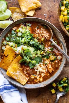 a bowl of mexican soup with tortilla chips and avocado on the side