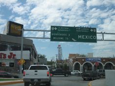 cars are driving down the street in front of a mexican restaurant and drive way sign