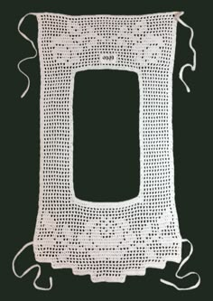 a white crocheted frame with a black background and string on the bottom that is attached to it