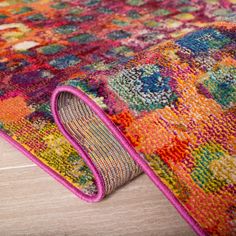 a multicolored area rug on the floor with a pink trimming around it