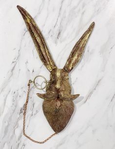 a gold rabbit head keychain on a marble surface with a chain attached to it