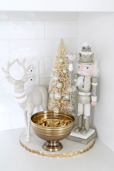 a christmas scene with a nutcracker and a gold bowl on a white counter