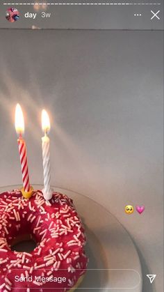 a donut with two candles on it sitting on a plate next to some candy