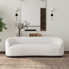 a white couch sitting next to a mirror on top of a wall