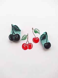 three cherries with leaves on them are hanging from earwires in the shape of cherry's