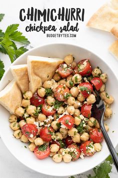 chickpea salad in a bowl with pita chips and cilantro on the side