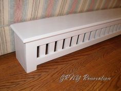 a white bench sitting on top of a hard wood floor next to a striped wall