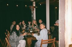 a group of people sitting around a table with drinks in front of them at night