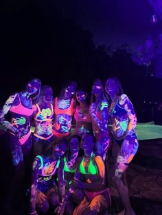 a group of people that are standing in the dark with glow paint on their bodies