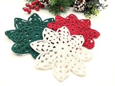 three crocheted snowflakes sitting next to pine cones