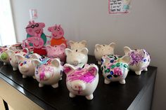 many pig figurines are painted in pink and blue on a black counter top