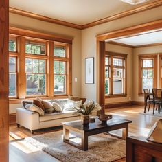 a living room filled with furniture and lots of wooden trim on the windows above them