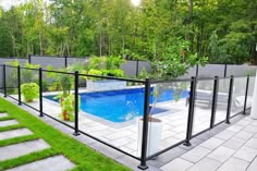 a glass fence around a swimming pool in a backyard