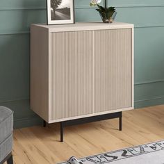 a white cabinet sitting on top of a hard wood floor next to a gray chair