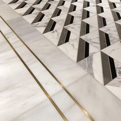 a marble floor with gold lines in the middle and black and white tiles on it