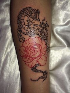 a dragon and rose tattoo on the leg