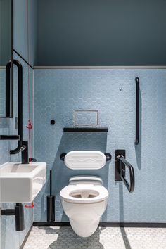 a white toilet sitting in a bathroom next to a wall mounted faucet and sink